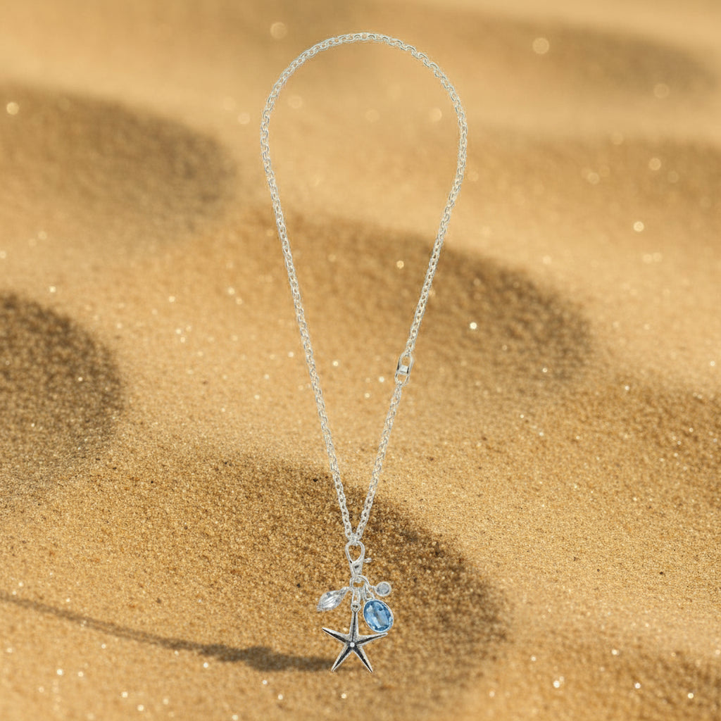 Necklace with a starfish pendant and blue gemstone on a sandy background