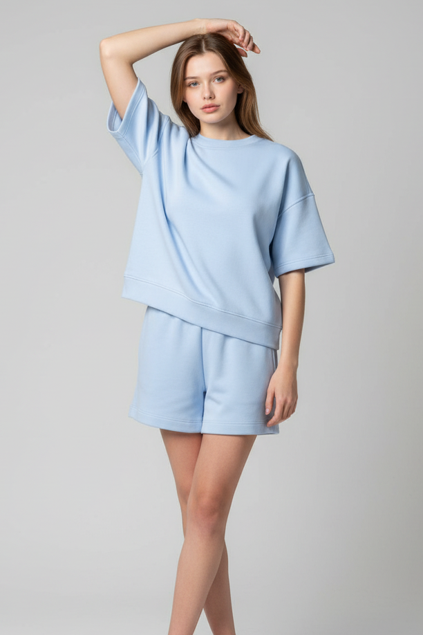 Woman wearing a light blue outfit with shorts on a plain background